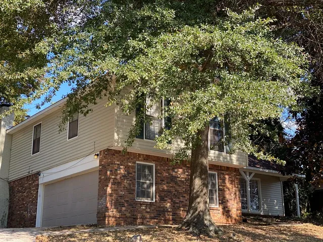 a front view of a house with a tree