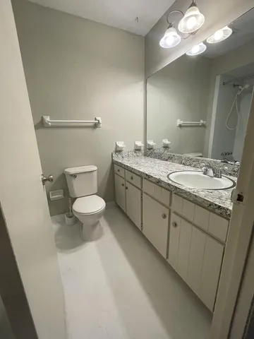 a spacious bathroom with a granite countertop sink a toilet and a mirror