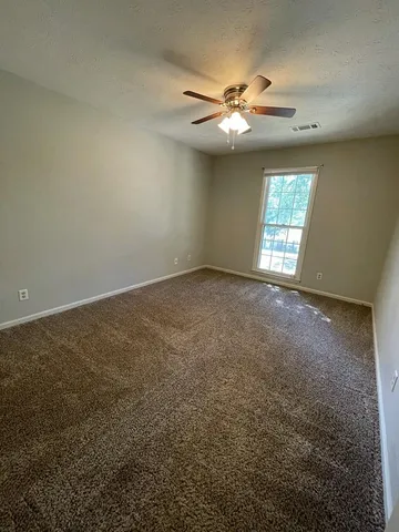 an empty room with windows and chandelier fan