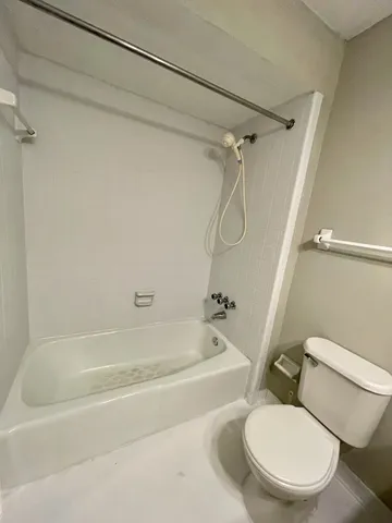 a white toilet sitting next to a bath tub and shower