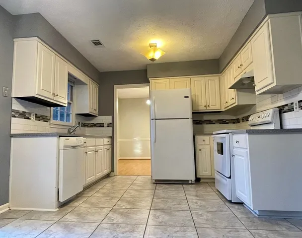 a kitchen with a refrigerator a stove top oven and cabinets