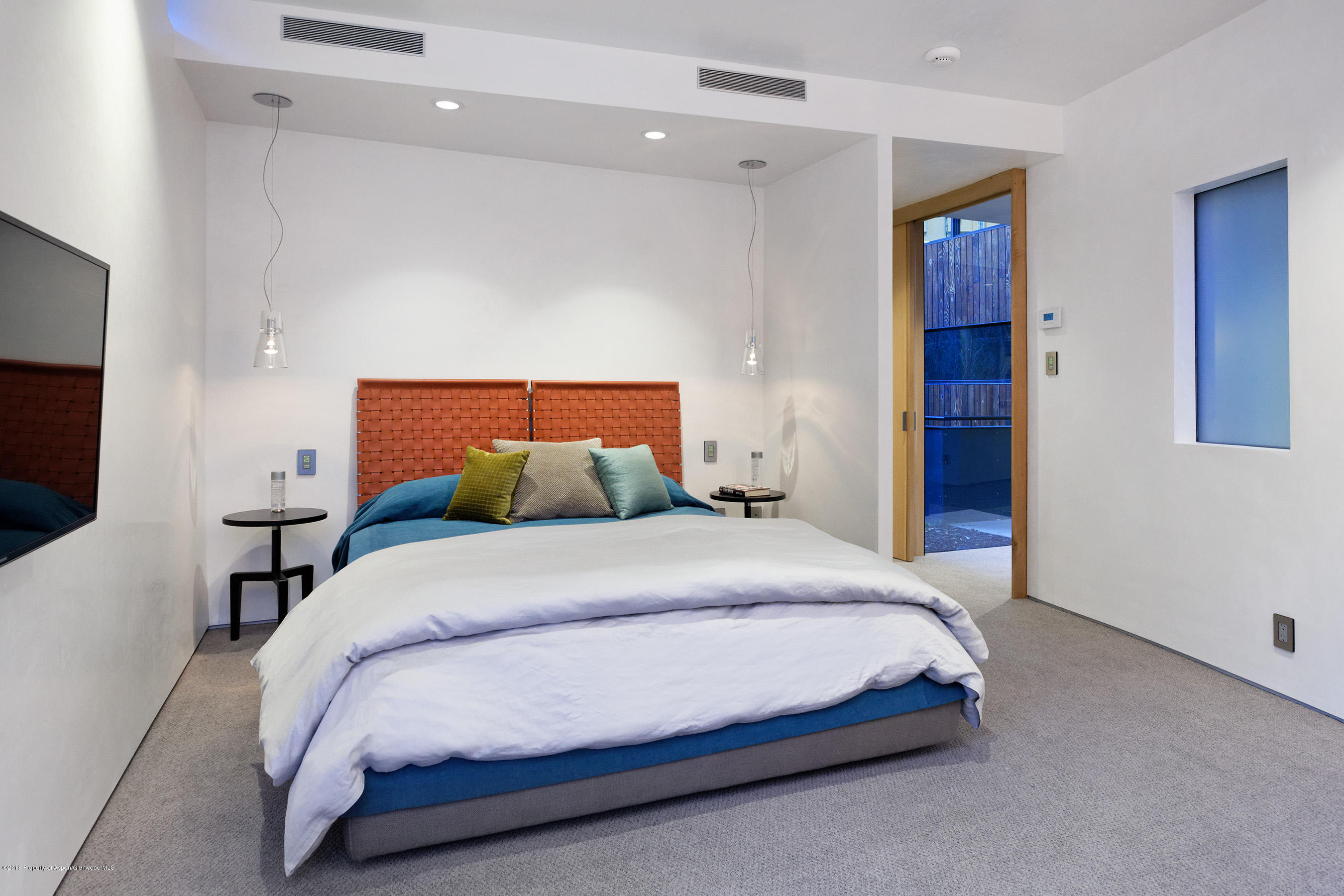 1118 Waters Avenue Aspen, CO 81611 - Photo 13 of 30 a bedroom with a bed and a flat tv screen on dresser