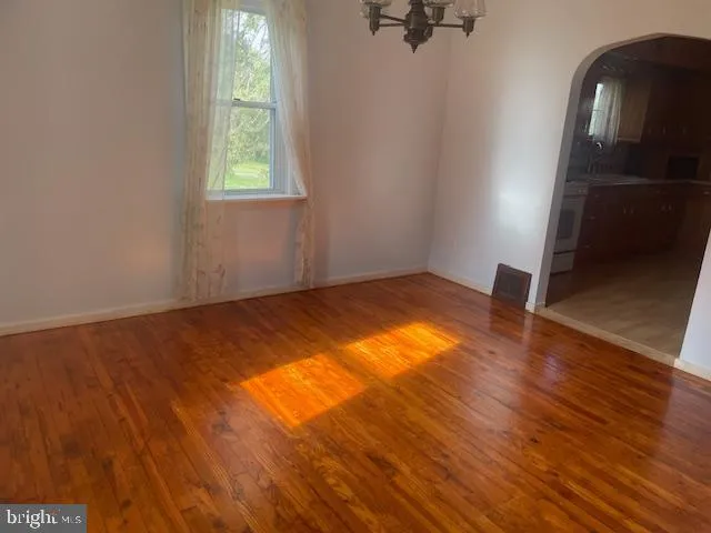 an empty room with wooden floor cabinet and windows