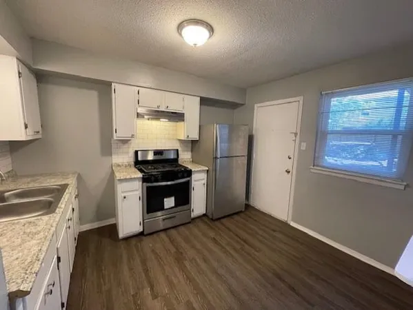 a kitchen with granite countertop a stove a sink and a refrigerator