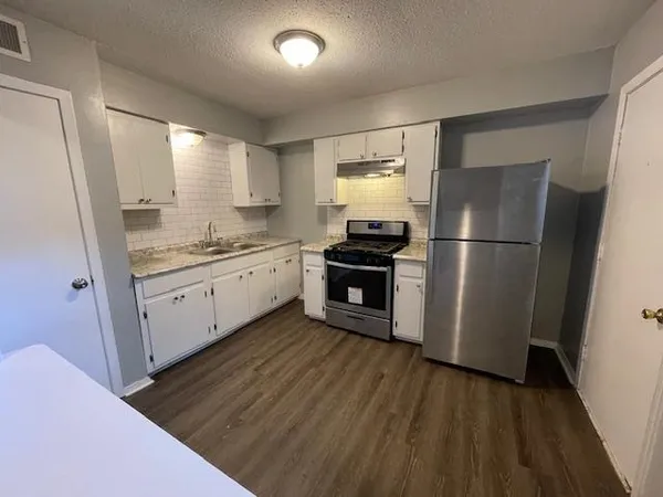 a kitchen with stainless steel appliances a refrigerator sink and wooden floor