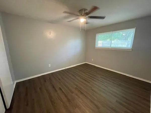 an empty room with wooden floor chandelier fan and window