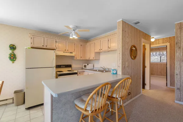 a kitchen with granite countertop a refrigerator a stove a sink dishwasher and white cabinets with wooden floor