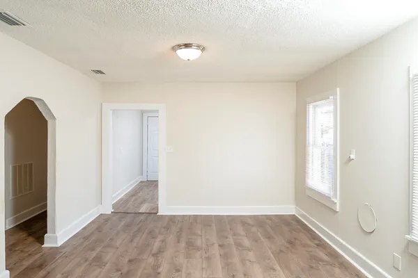 an empty room with wooden floor and windows