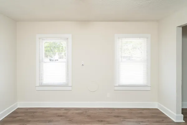 an empty room with wooden floor and windows