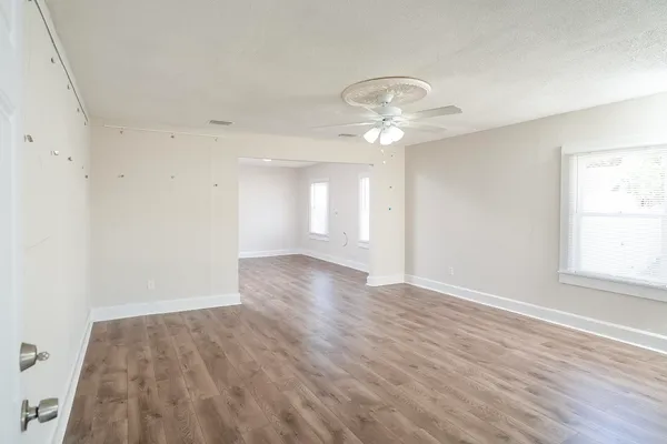 an empty room with wooden floor and windows