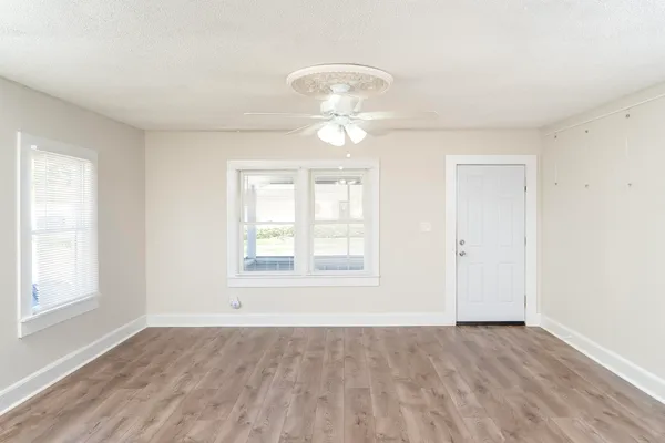 a view of an empty room with a window and wooden floor