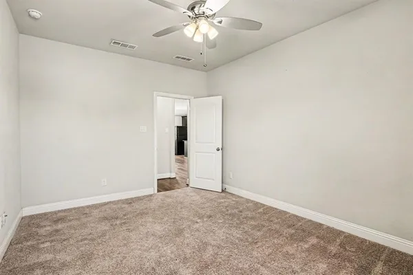 an empty room with chandelier fan and closet area