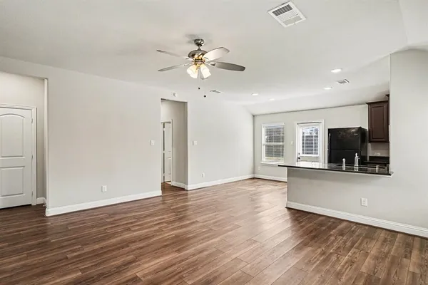 a view of a livingroom with wooden floor a ceiling fan and windows