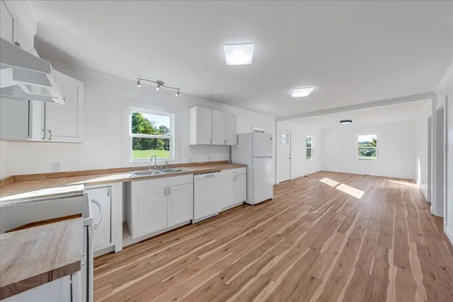 a kitchen with granite countertop a stove a sink and white cabinets with wooden floor
