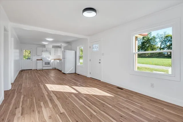 a view of empty room with wooden floor and window
