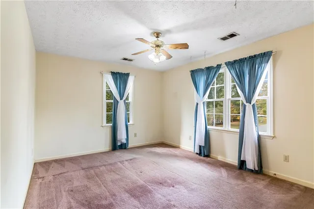 an empty room with windows and ceiling fan