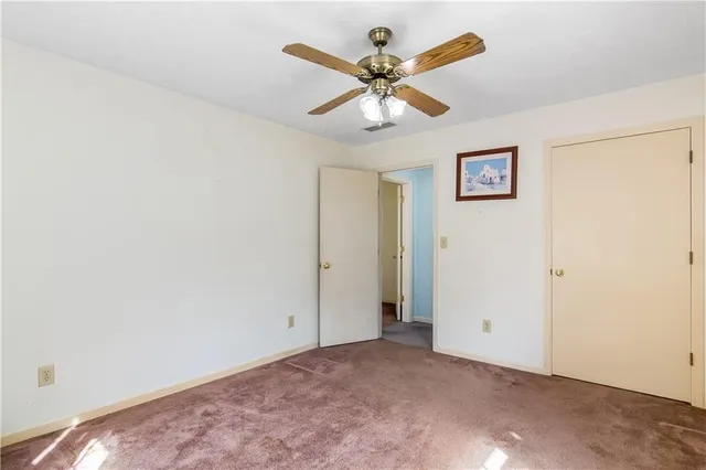 an empty room with a ceiling fan and a window