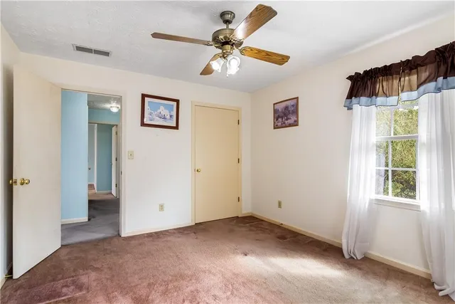 a view of empty room with window and ceiling fan