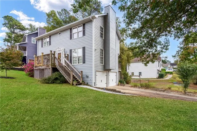 a view of a house with a big yard potted plants and a large tree