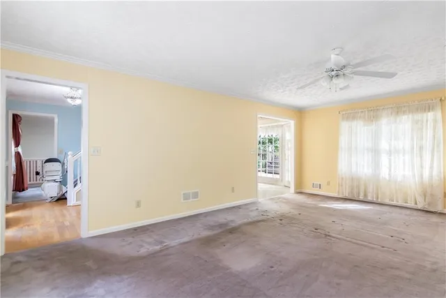 a view of empty room with window and ceiling fan
