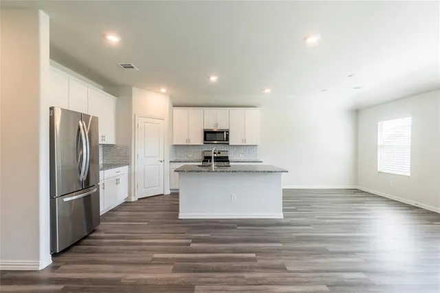 a view of kitchen with microwave refrigerator and cabinets