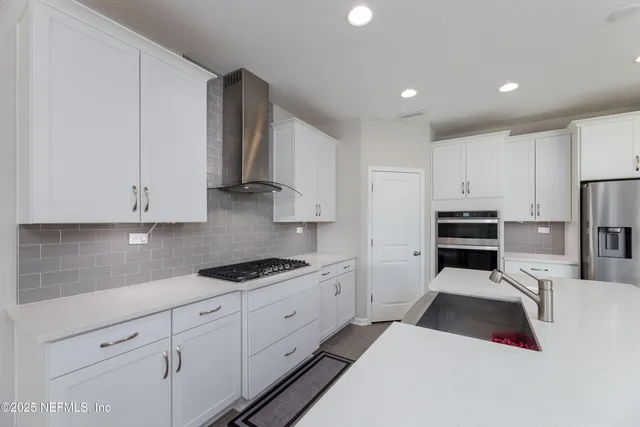 a kitchen with white cabinets and stainless steel appliances