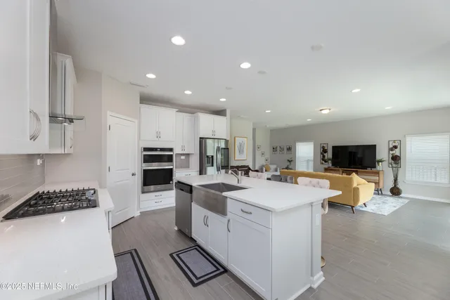 a large white kitchen with lots of counter space a sink appliances and cabinets