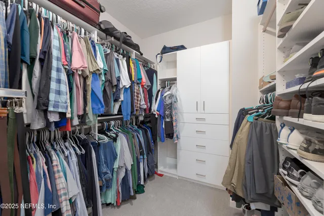 a view of walk in closet with clothes and shoes