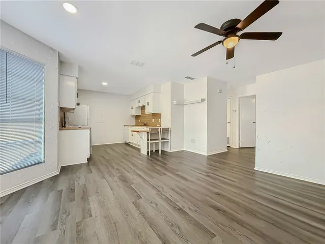 a view of empty room with wooden floor and ceiling fan