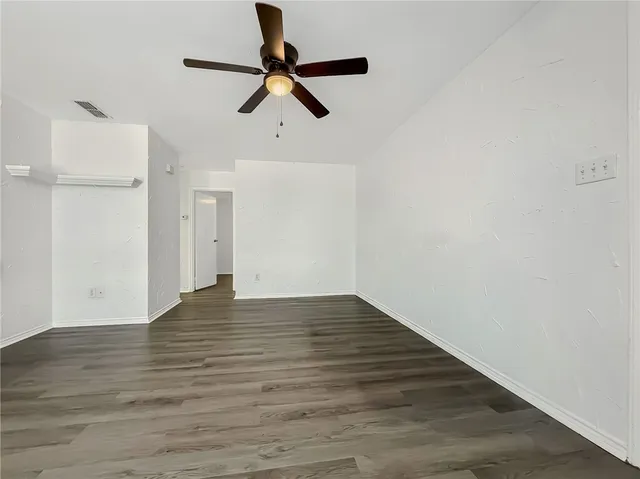 a view of empty room with wooden floor and ceiling fan