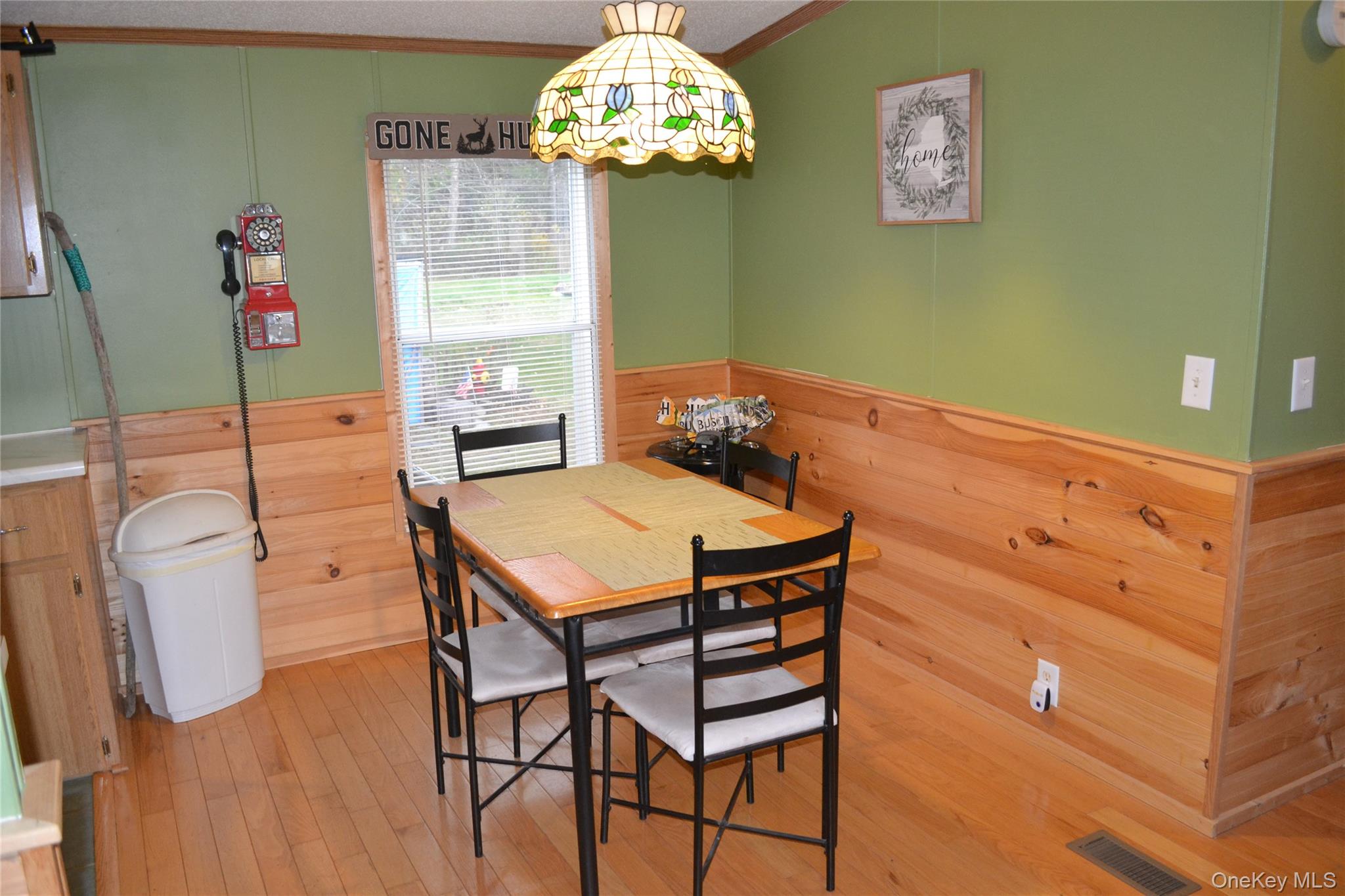144 Bonnie Brook Road Roscoe, NY 12776 - Photo 10 of 34 Dining area featuring wooden walls, a wainscoted wall, wood-type flooring, ornamental molding, and a textured ceiling