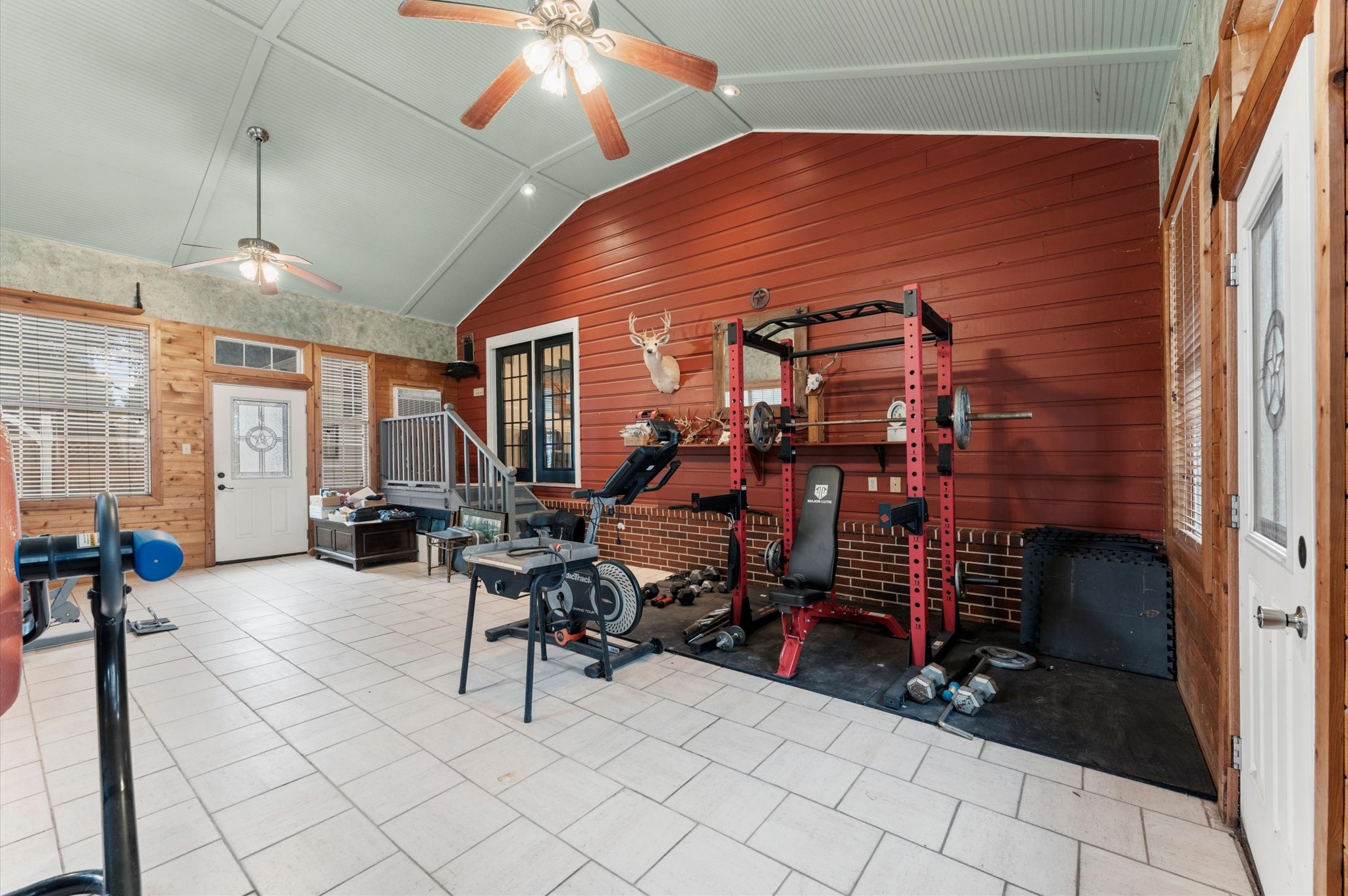 22634 Park Road Tomball, TX 77377 - Photo 14 of 29 Spacious home gym with high ceilings, featuring a red accent wall and ample natural light, perfect for fitness enthusiasts.