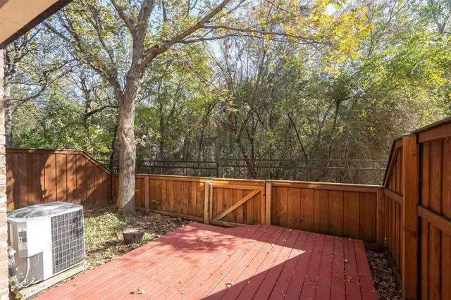 a view of a backyard with wooden floor and large trees