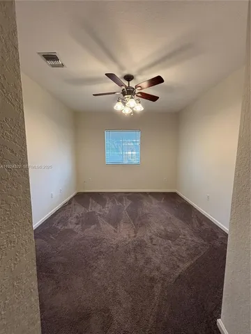 an empty room with windows and chandelier fan
