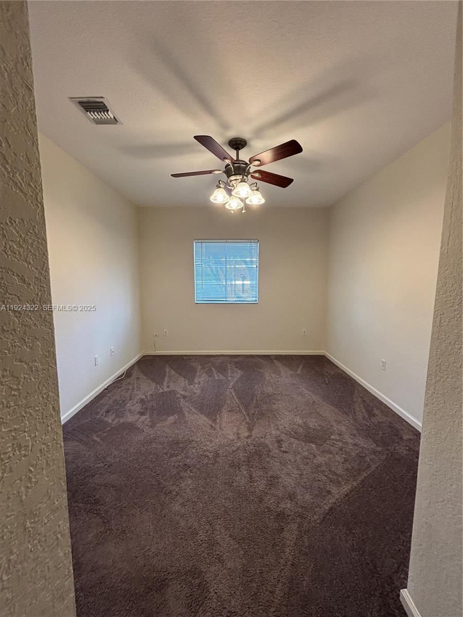 6533 Catalina Lane, Unit 6533 Tamarac, FL 33321 - Photo 13 of 27 an empty room with windows and chandelier fan