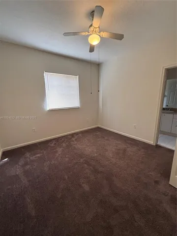 an empty room with a window and a ceiling fan