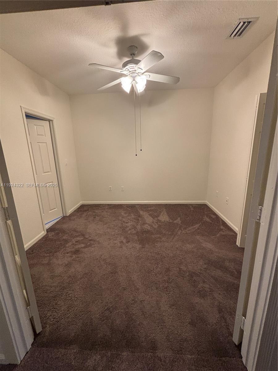 6533 Catalina Lane, Unit 6533 Tamarac, FL 33321 - Photo 25 of 27 an empty room with a chandelier fan and wooden floor