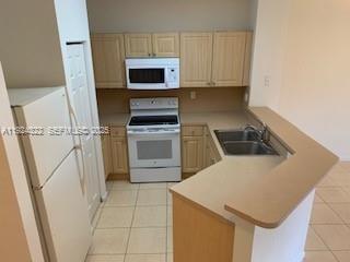 6533 Catalina Lane, Unit 6533 Tamarac, FL 33321 - Photo 5 of 27 a kitchen with a sink a stove a microwave and cabinets