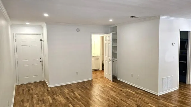 a view of an empty room with wooden floor and closet