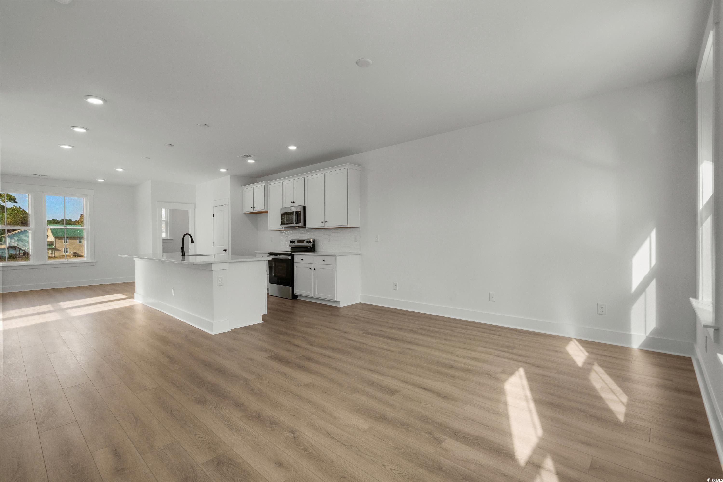 4414 Kingsport Road, Unit 1402 Little River, SC 29566 - Photo 34 of 34 Kitchen with open floor plan, a kitchen island with sink, white cabinetry, appliances with stainless steel finishes, and light wood-type flooring