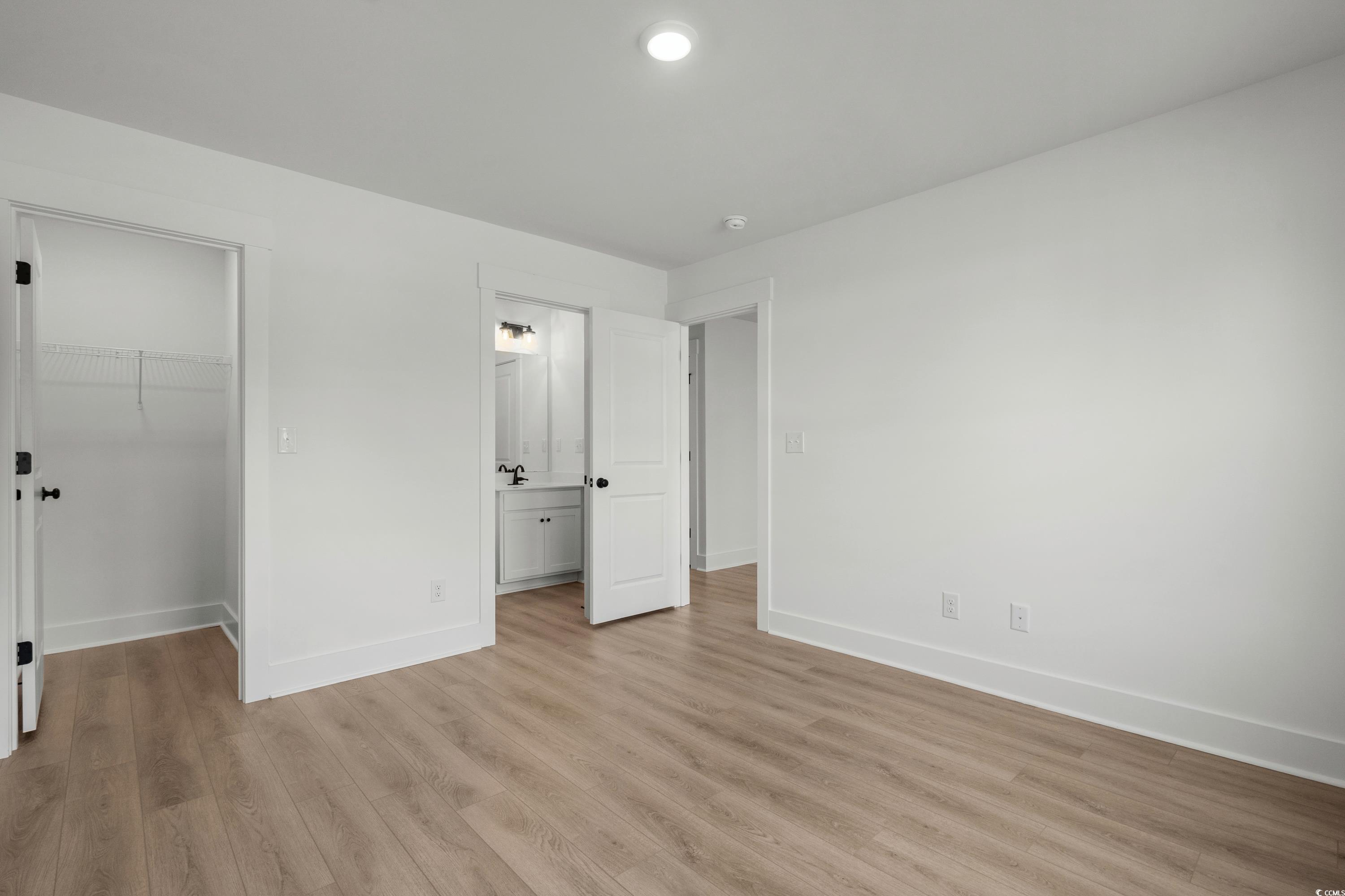 4414 Kingsport Road, Unit 1402 Little River, SC 29566 - Photo 25 of 34 Unfurnished bedroom with a walk in closet, light wood finished floors, and ensuite bath
