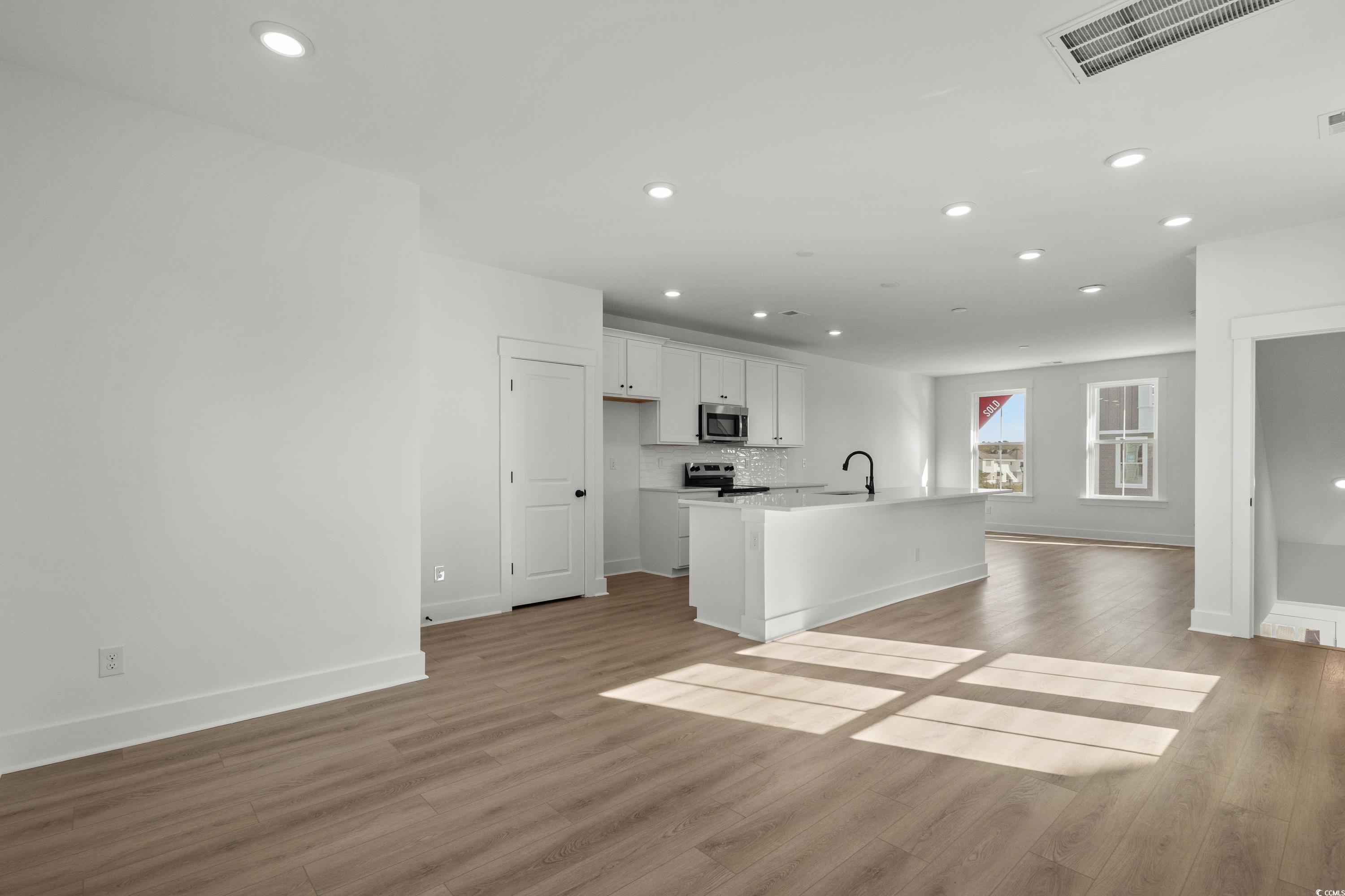 4414 Kingsport Road, Unit 1402 Little River, SC 29566 - Photo 33 of 34 Kitchen featuring white cabinetry, recessed lighting, an island with sink, open floor plan, and light wood-style floors