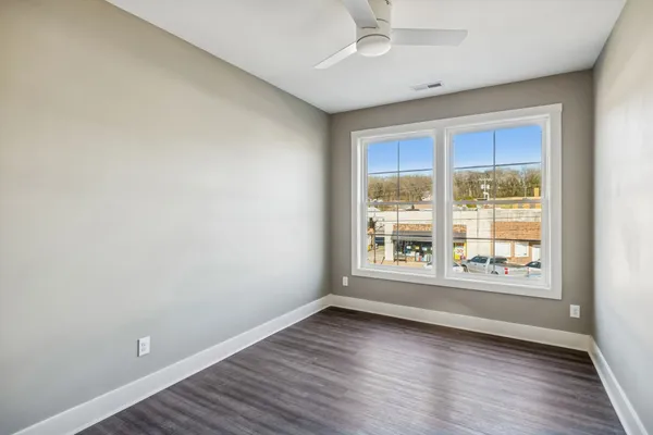 an empty room with wooden floor and windows