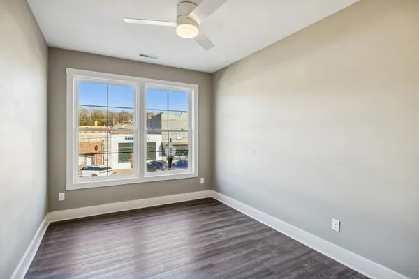 an empty room with wooden floor and windows