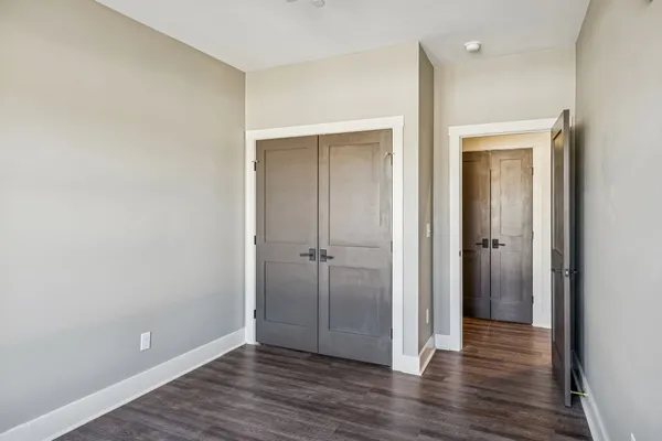 an empty room with wooden floor & closet area