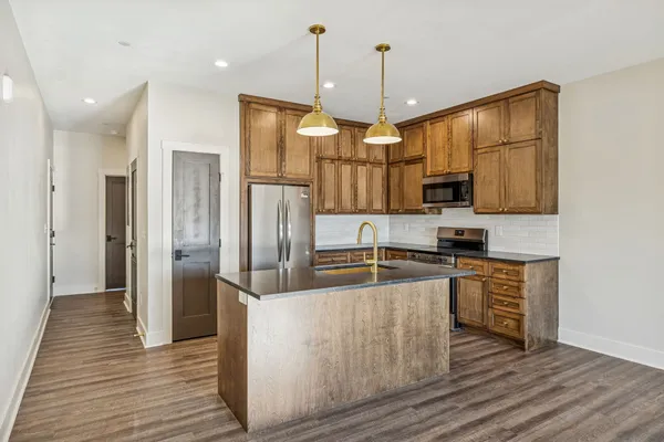 a kitchen with stainless steel appliances granite countertop a refrigerator a oven a stove and a wooden floors