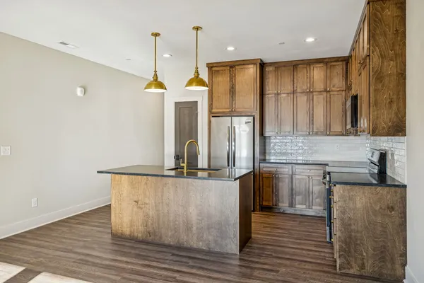 a kitchen with stainless steel appliances granite countertop a refrigerator a sink and a stove