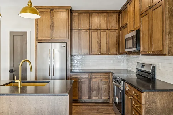 a kitchen with stainless steel appliances granite countertop a sink a stove and a refrigerator