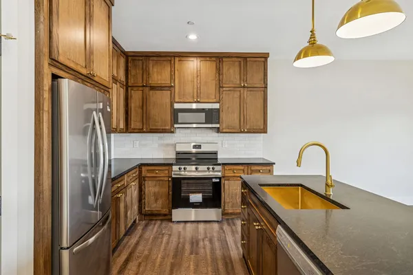a kitchen with stainless steel appliances granite countertop a sink a stove and refrigerator