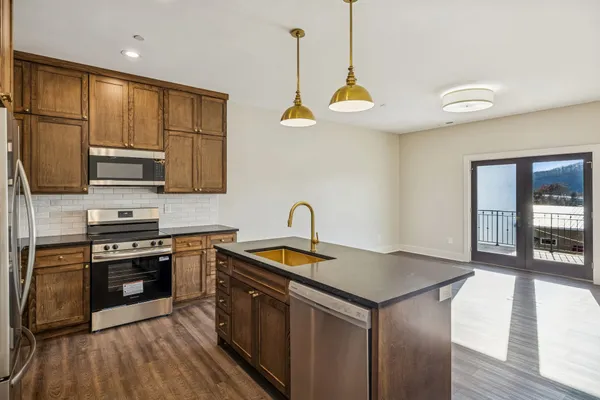 a kitchen with stainless steel appliances granite countertop a sink a stove and a wooden floors